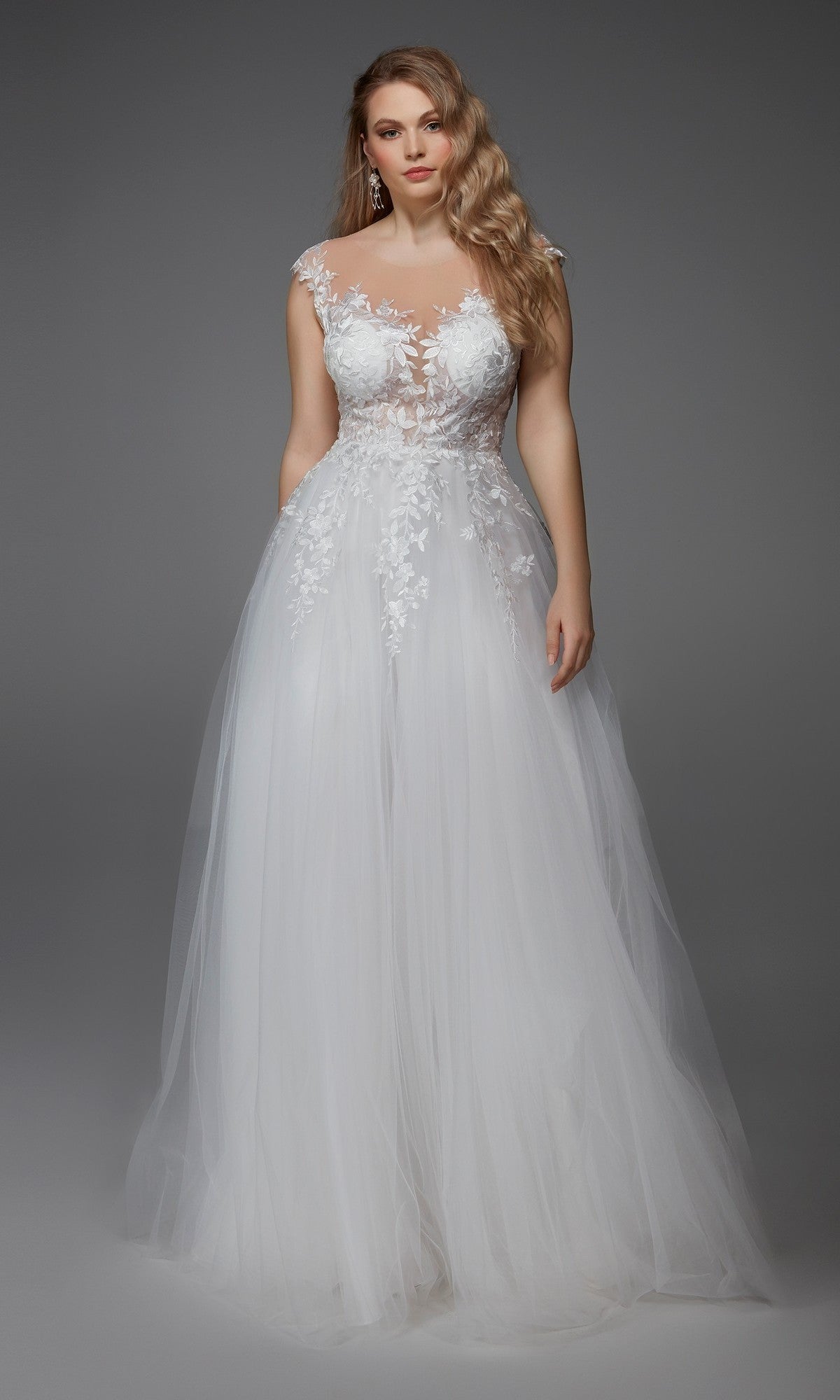 A woman wears the Alyce 5090 long formal dress in ivory, featuring a sleeveless lace embroidered bodice and an A-line tulle skirt, standing against a plain gray background.